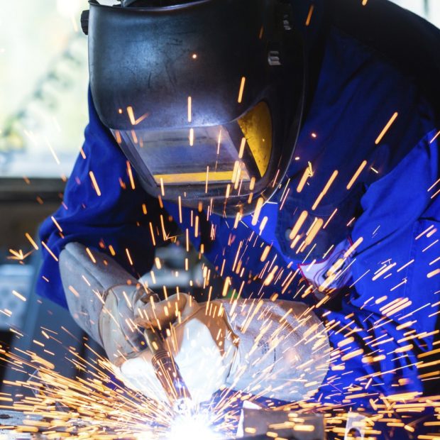 Welder welding metal in workshop with sparks