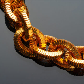 Golden chain necklace on black background with reflection close up